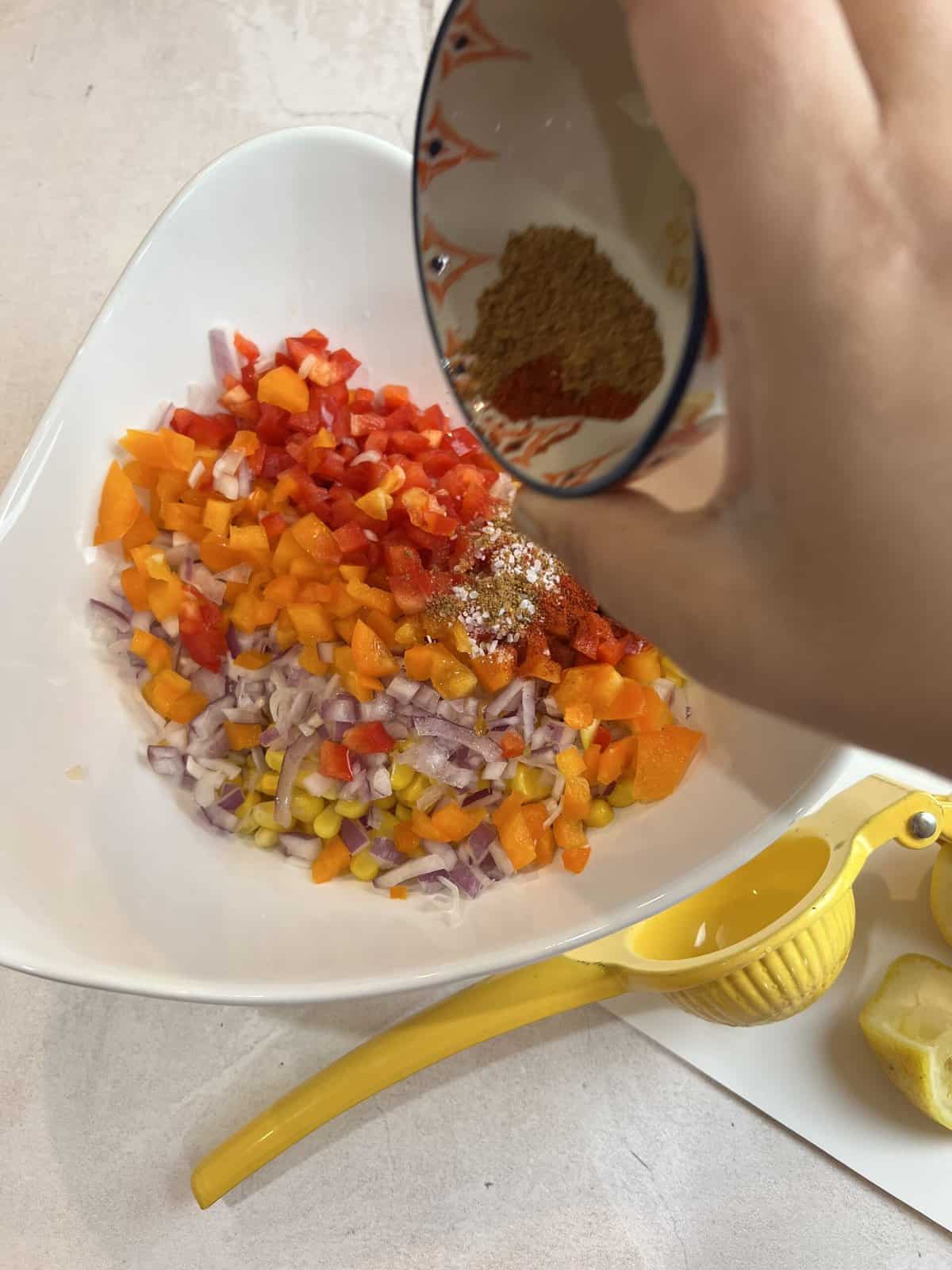 white bowl with mixed corn salad and a small bowl of spices.