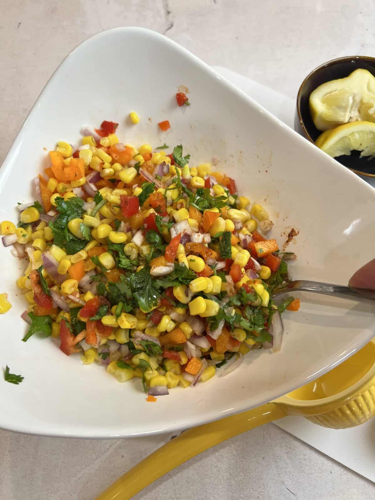 mixed corn salad in a white bowl.