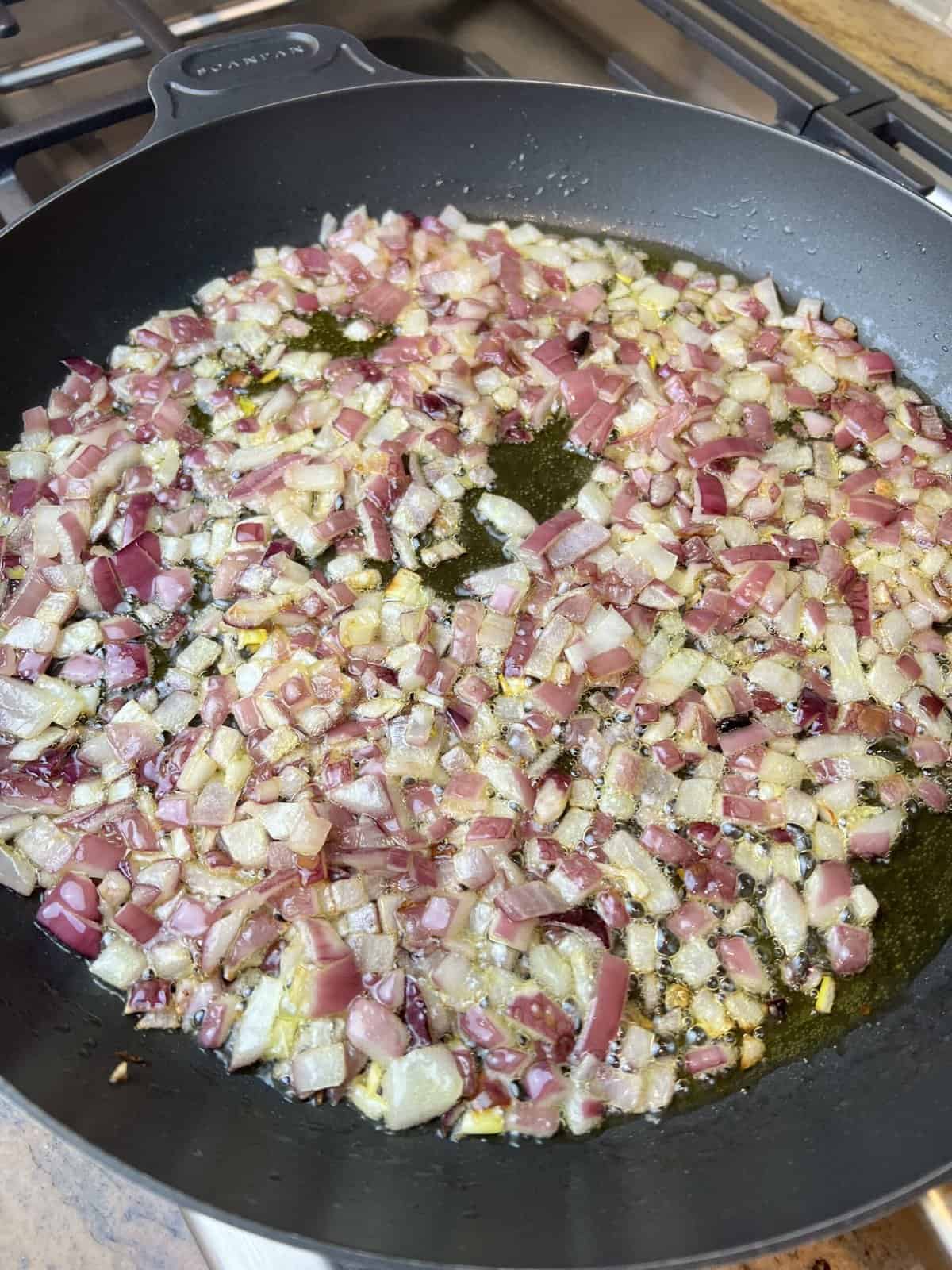 black frying pan with red onions.