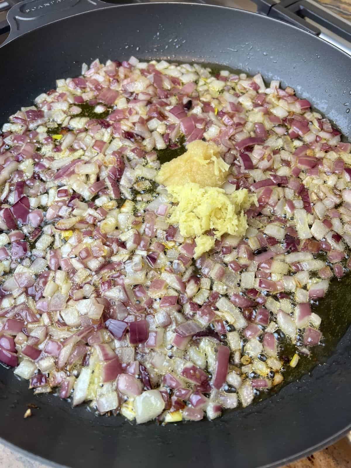 black pan with red onions, and ginger garlic paste.