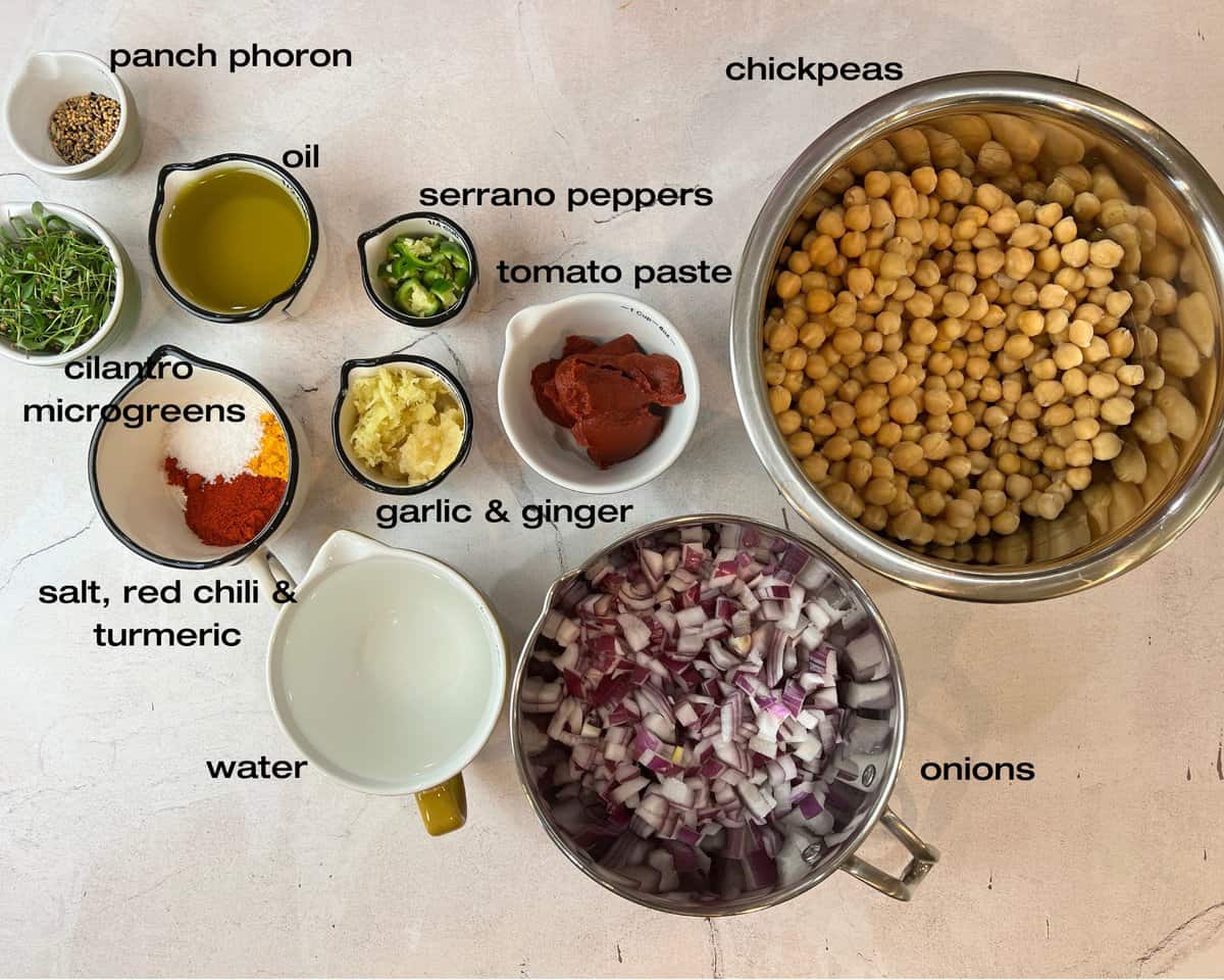 beige board with chickpeas, onions, ginger garlic paste, tomato paste, spice blend, cilantro, peppers, oil and water.