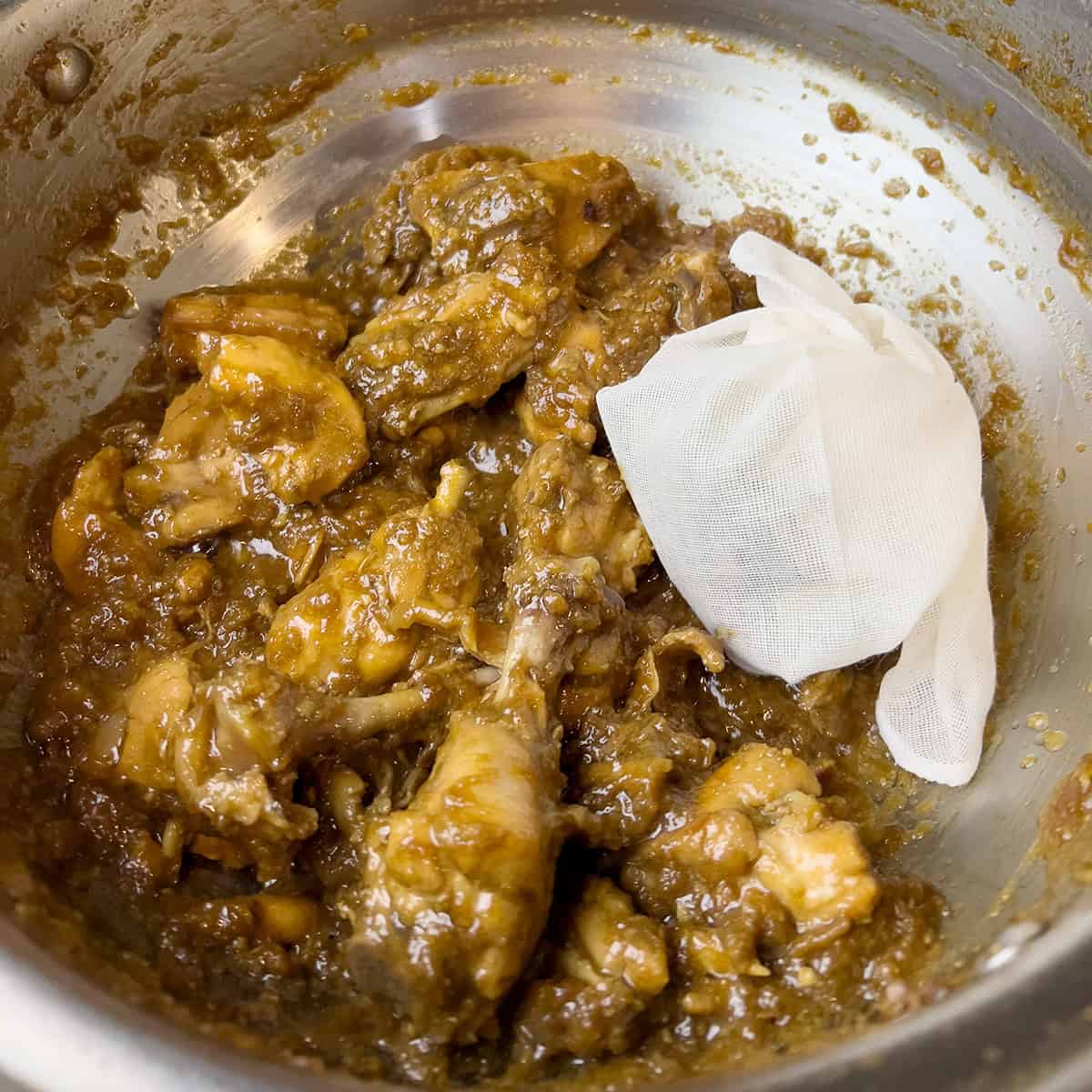 Cooked chicken with a pouch of whole spices.