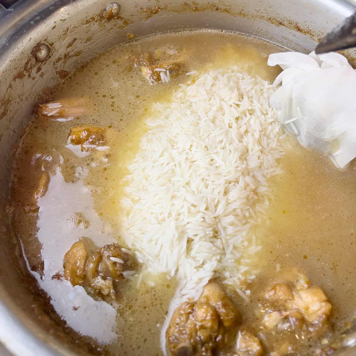 Chicken and rice being cooked for a Pakistani recipe.
