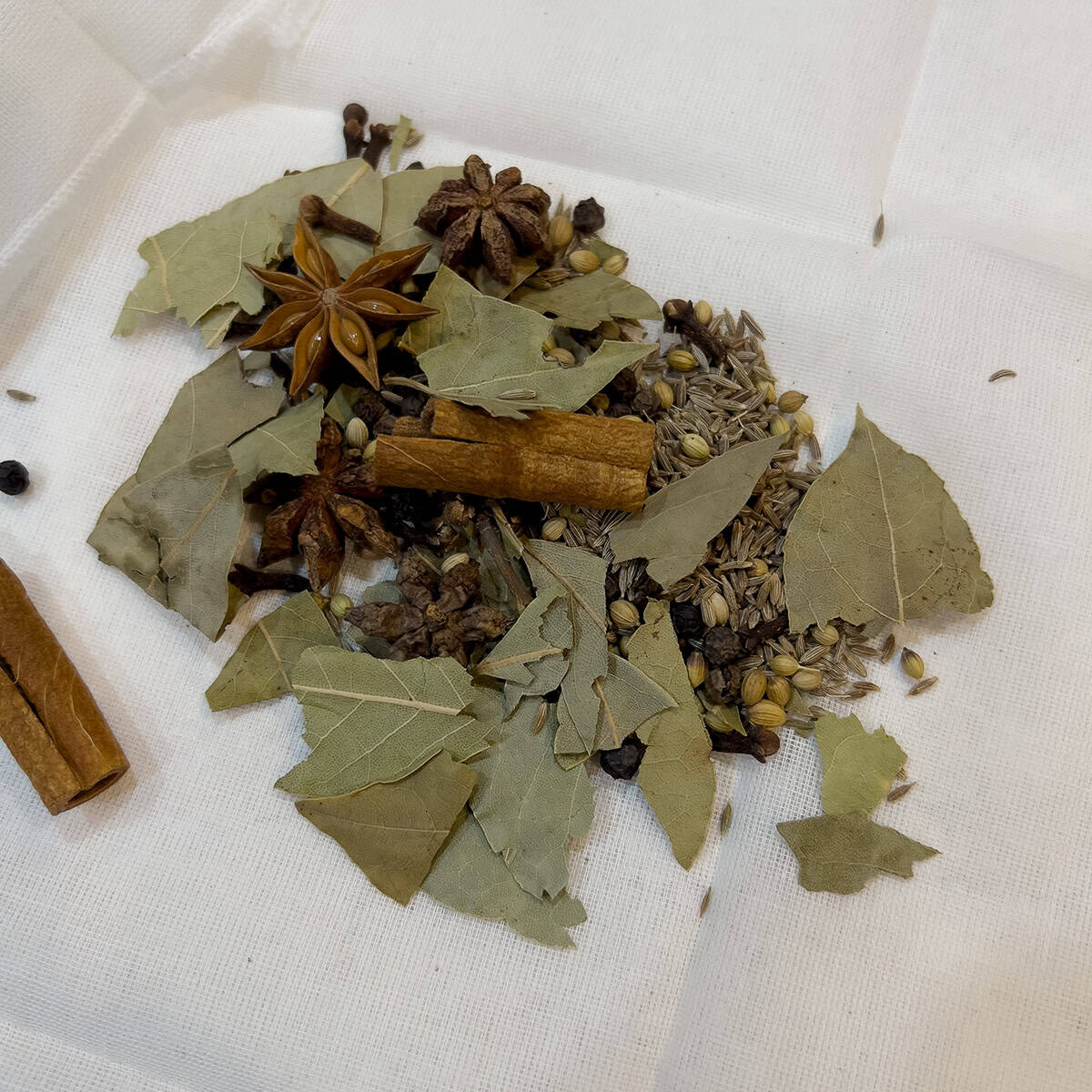 Whole spices being prepped into a bouquet garni for a recipe.