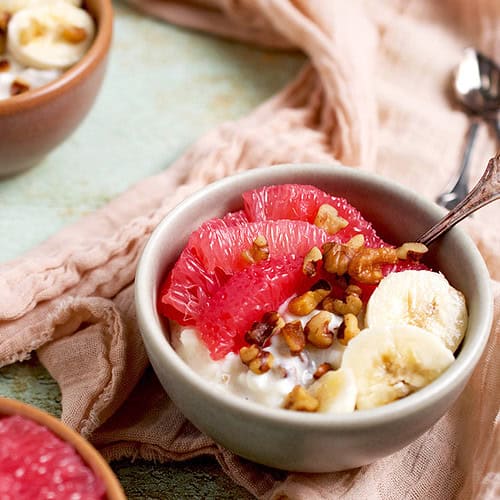 A breakfast bowl made of cottage cheese, grapefruit, bananas and walnuts is ready to be served.