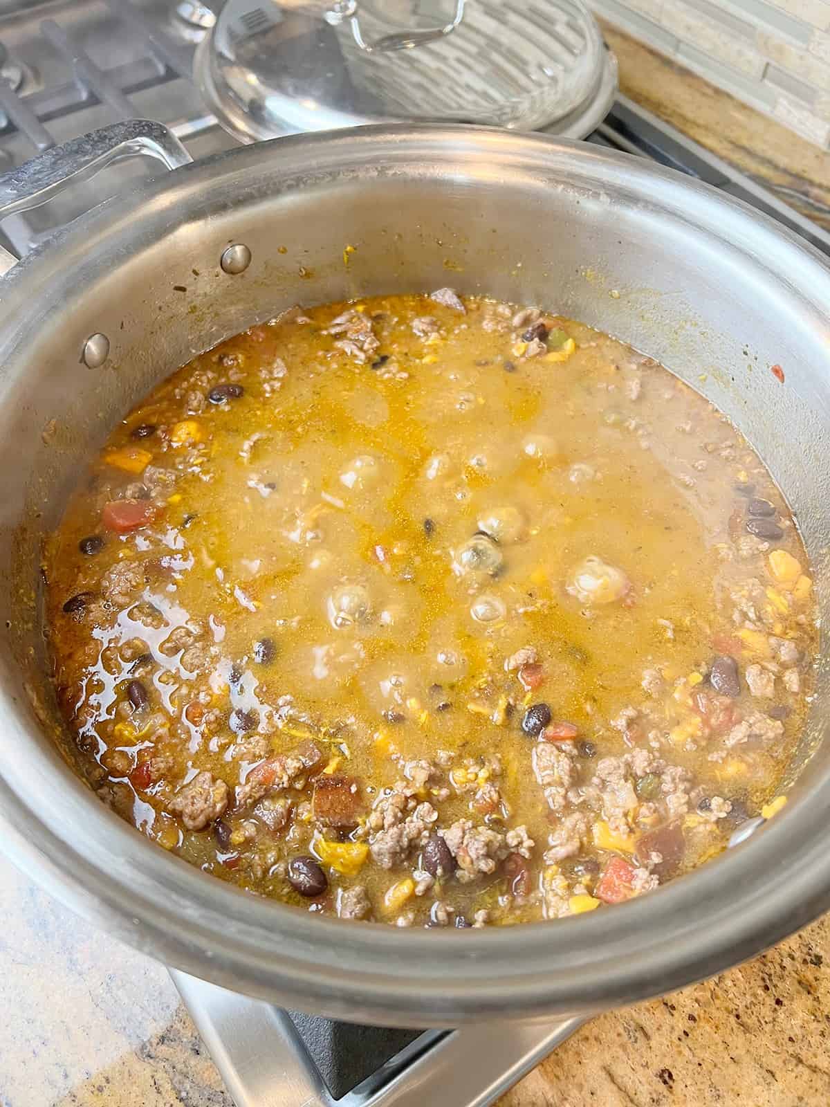 A stainless steel pot with  a sweet potato and black bean chili simmering in it.