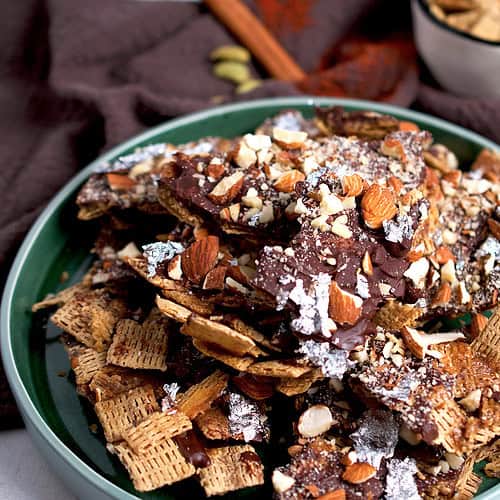 Chex mix layered with toffee, chocolate and almonds is plated.