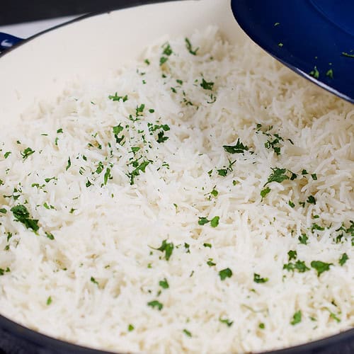 A freshly cooked pot of basmati rice garnished with cilantro is ready to serve.