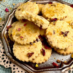 Freshly baked shortbread cookies with rose, pistachio and cardamom are plated in a silver plate.