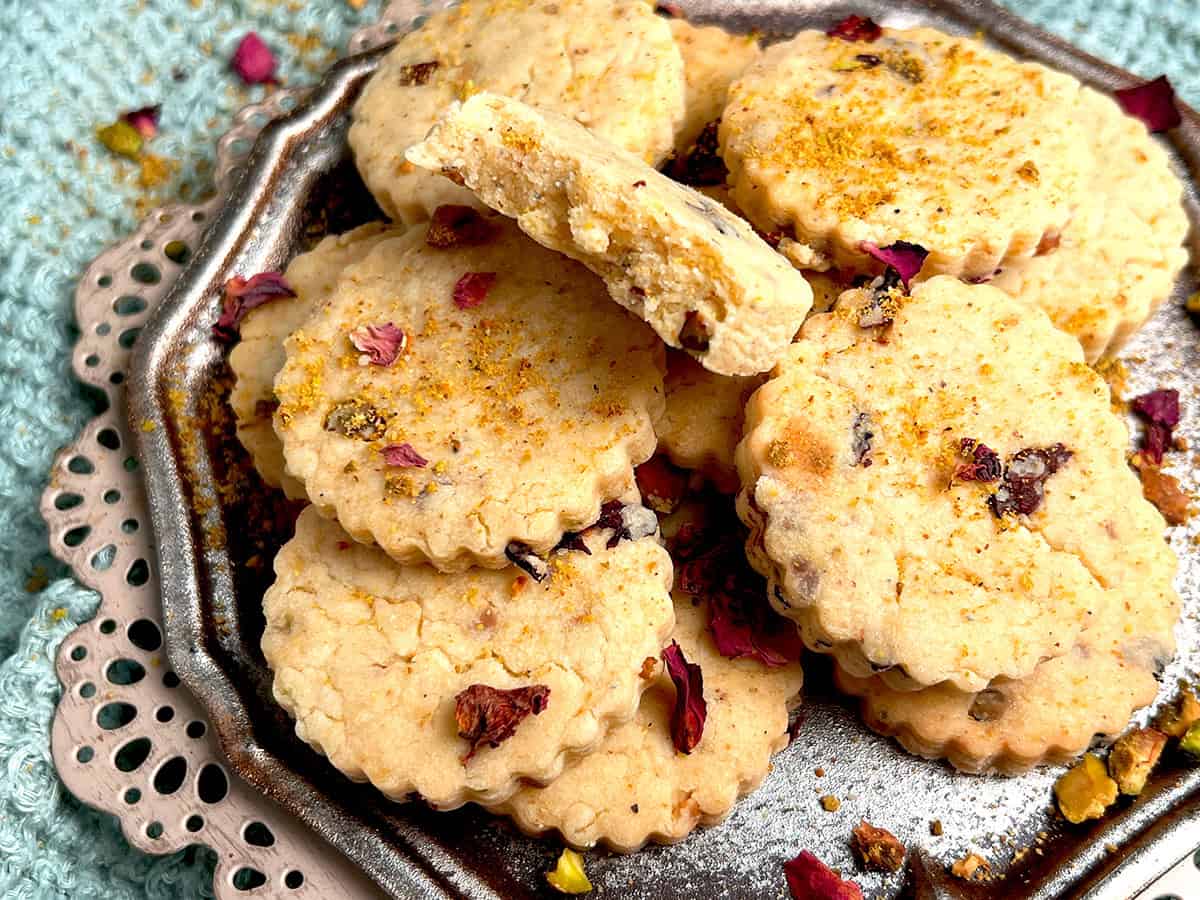 Shortbread cookies infused with rose petals, pistachios and cardamom are served in a silver platter.