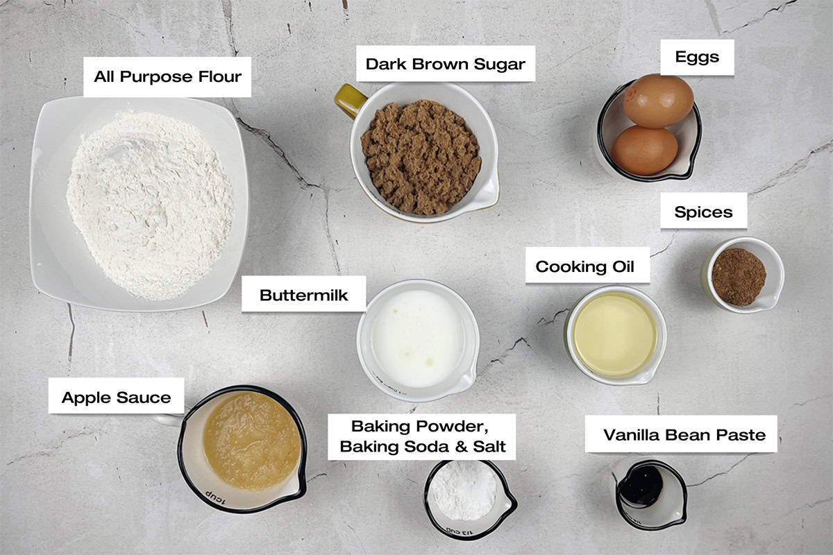 Ingredients to make a holiday spice cake are lying on a white kitchen counter.