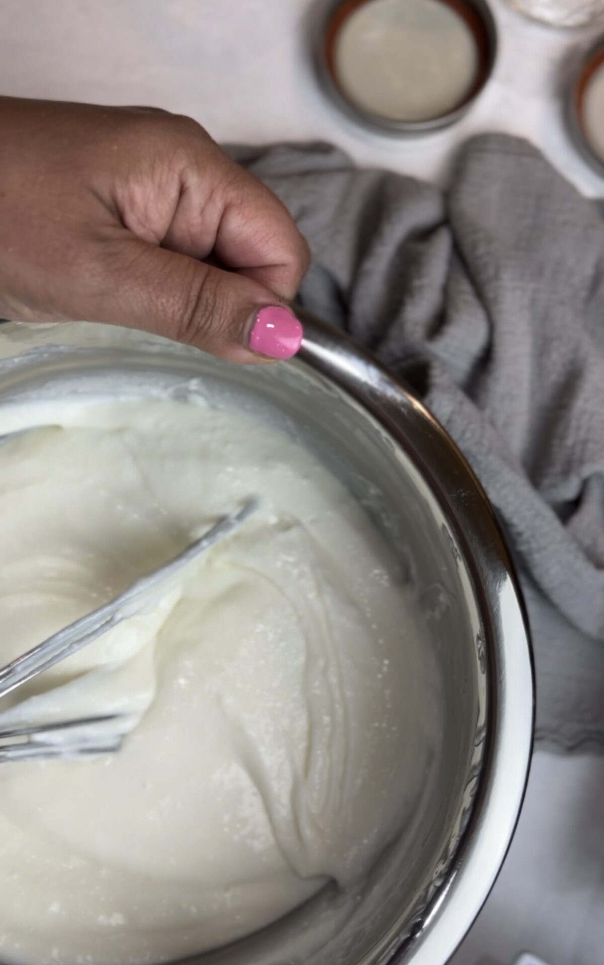 silver bowl with a hand holding a whisk and whipping ricotta for a breakfast parfait.