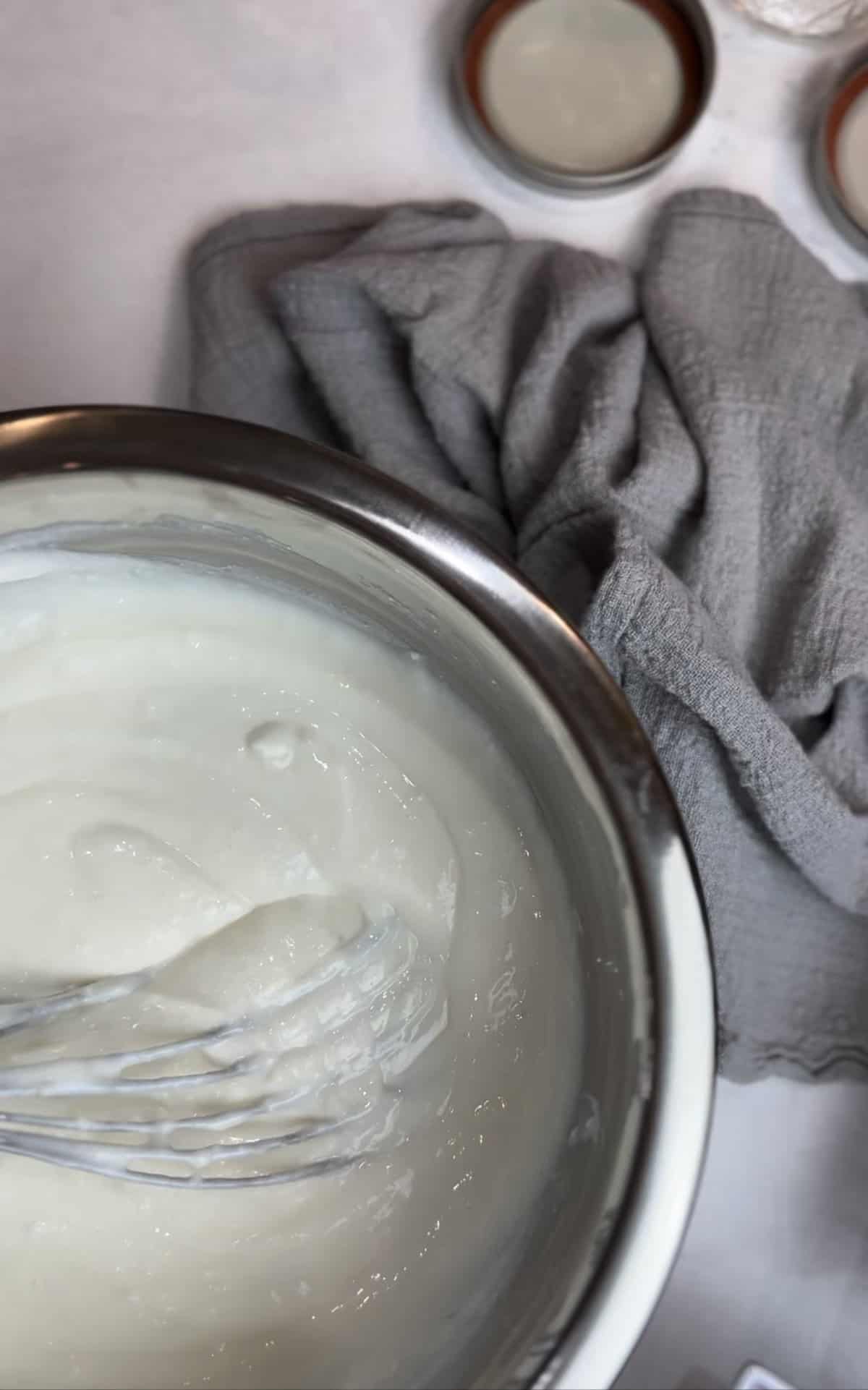 silver bowl with whipped ricotta and yogurt for a breakfast parfait on a white counter with a grey napkin.