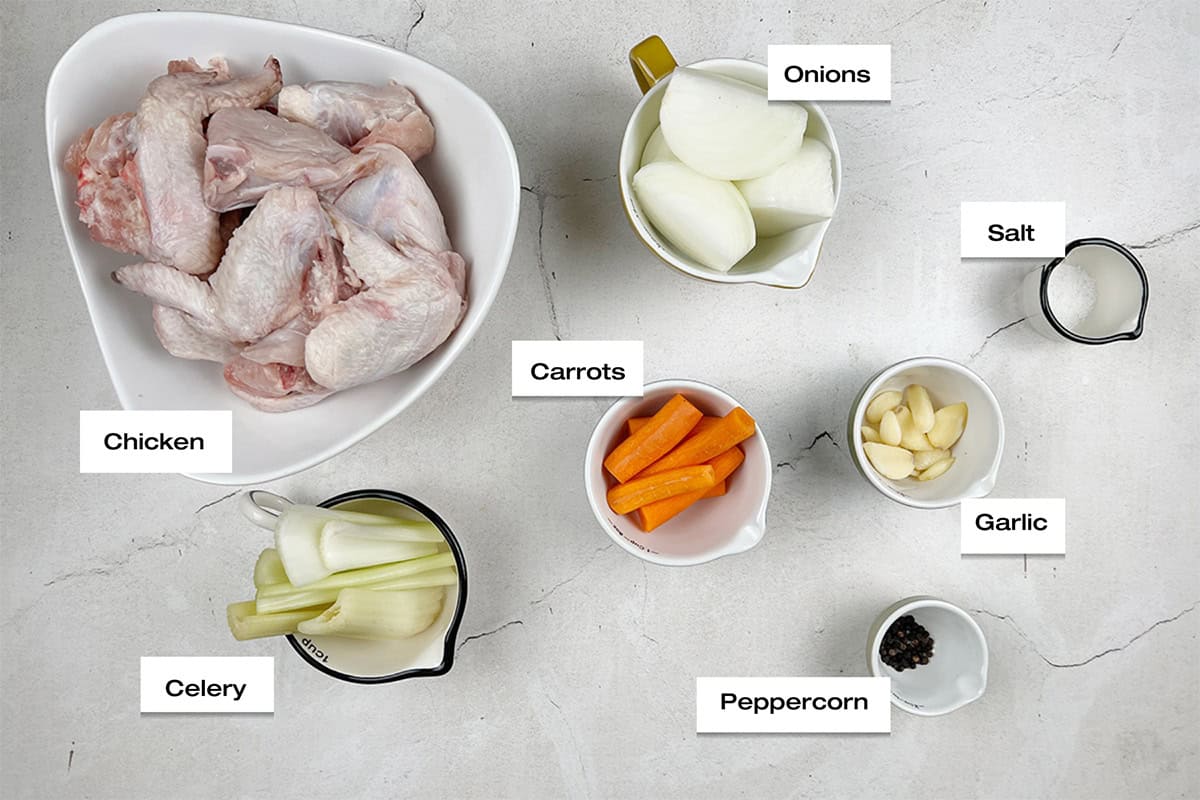 Ingredients to cook a homemade chicken broth recipe are lying on a kitchen counter.