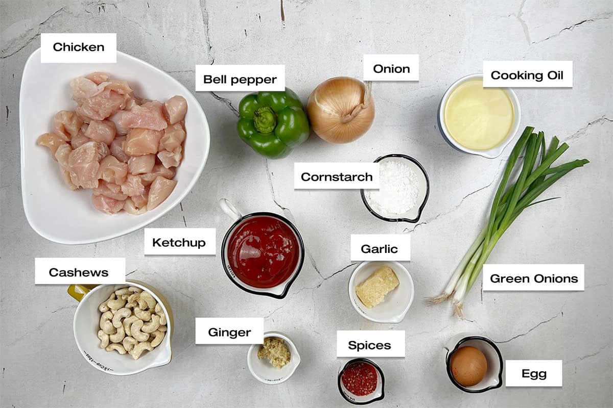 Ingredients to cook and Indo-Chinese style chicken recipe are lying on a white kitchen counter.