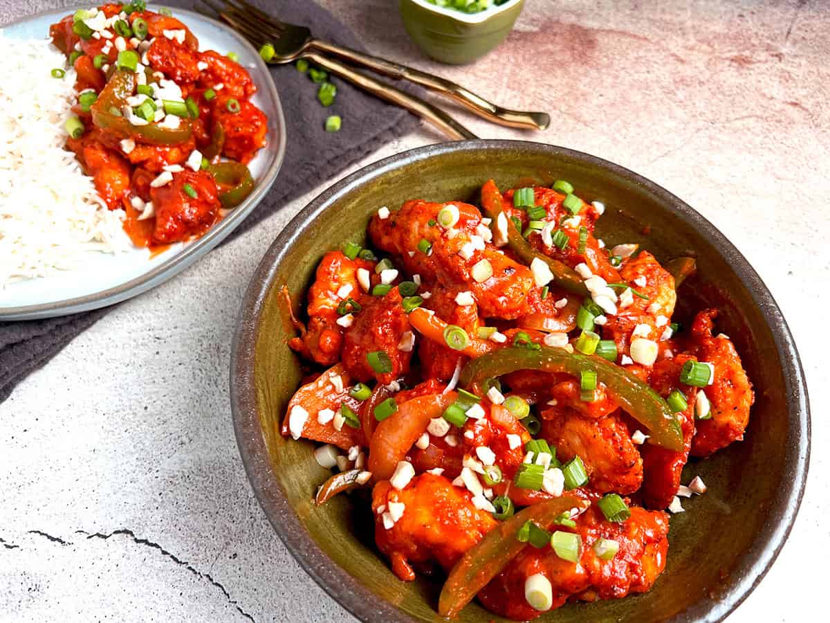 Indo-Chinese style chili chicken recipe is served in an olive green bowl.