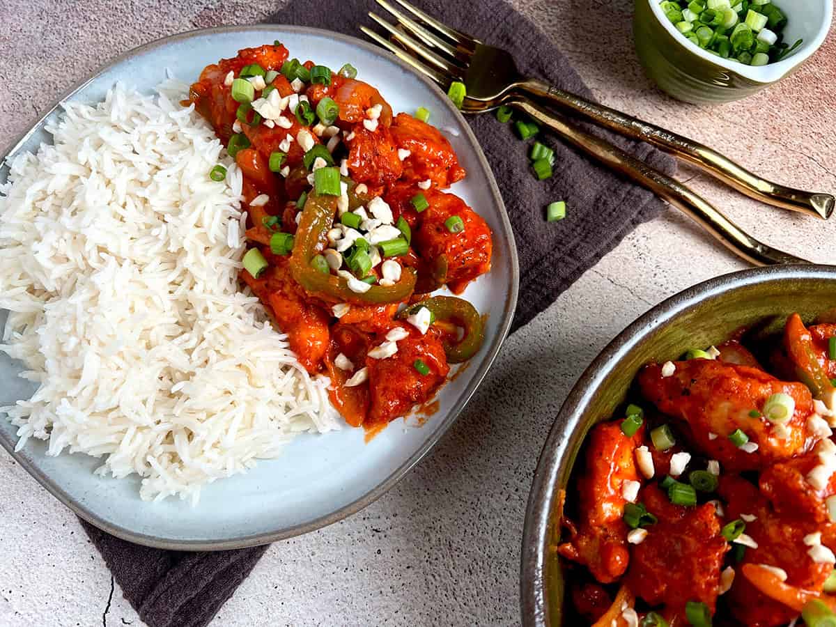 A plate of rice and spicy and crispy chili chicken is being served for dinner.
