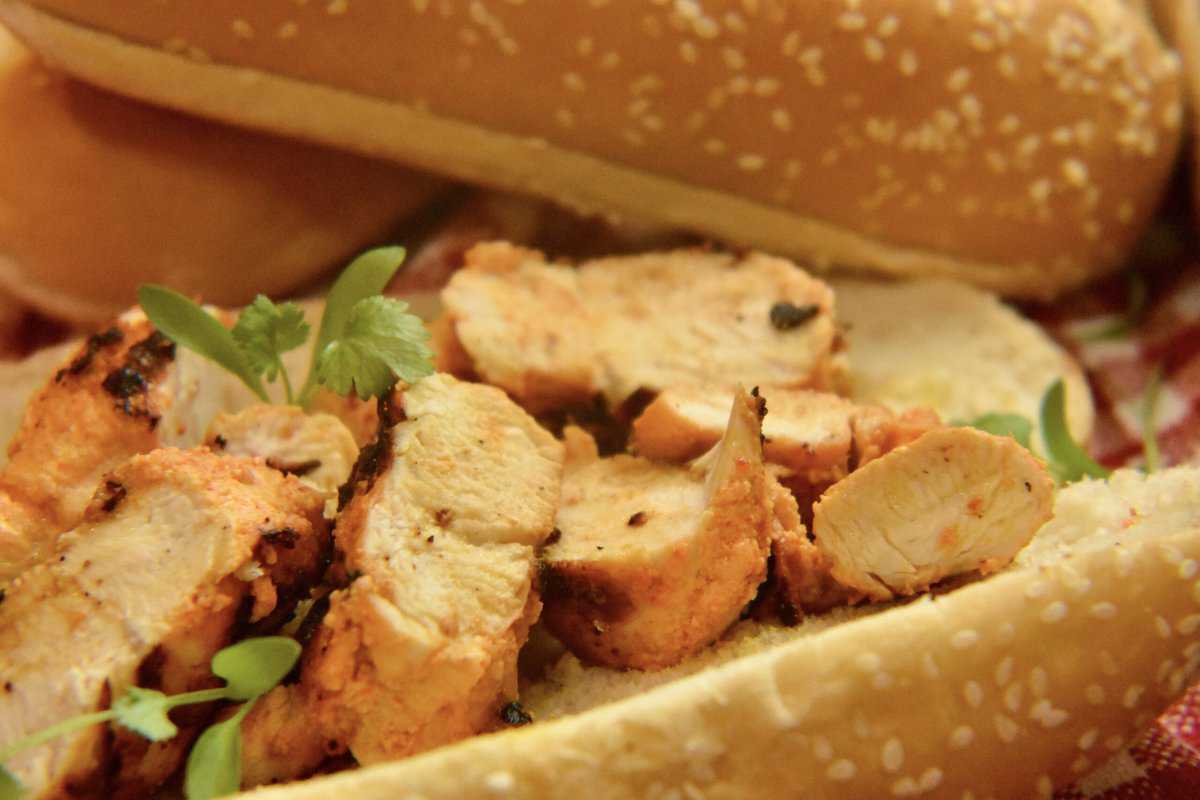 bread roll with chicken tikka pieces and microgreens