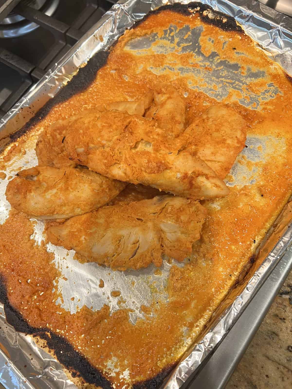 cooked chicken tikka tenderloins in tray covered in foil.