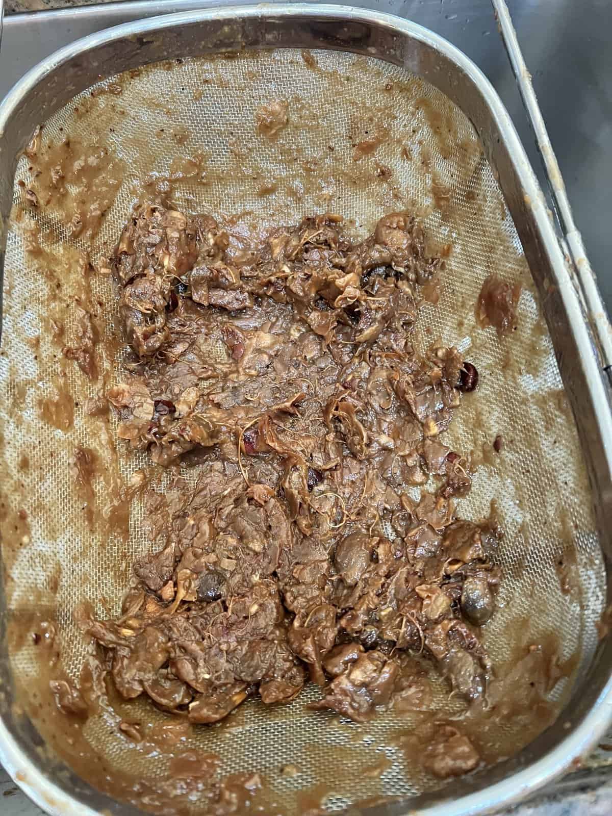 tamarind seeds and fibre in a strainer.