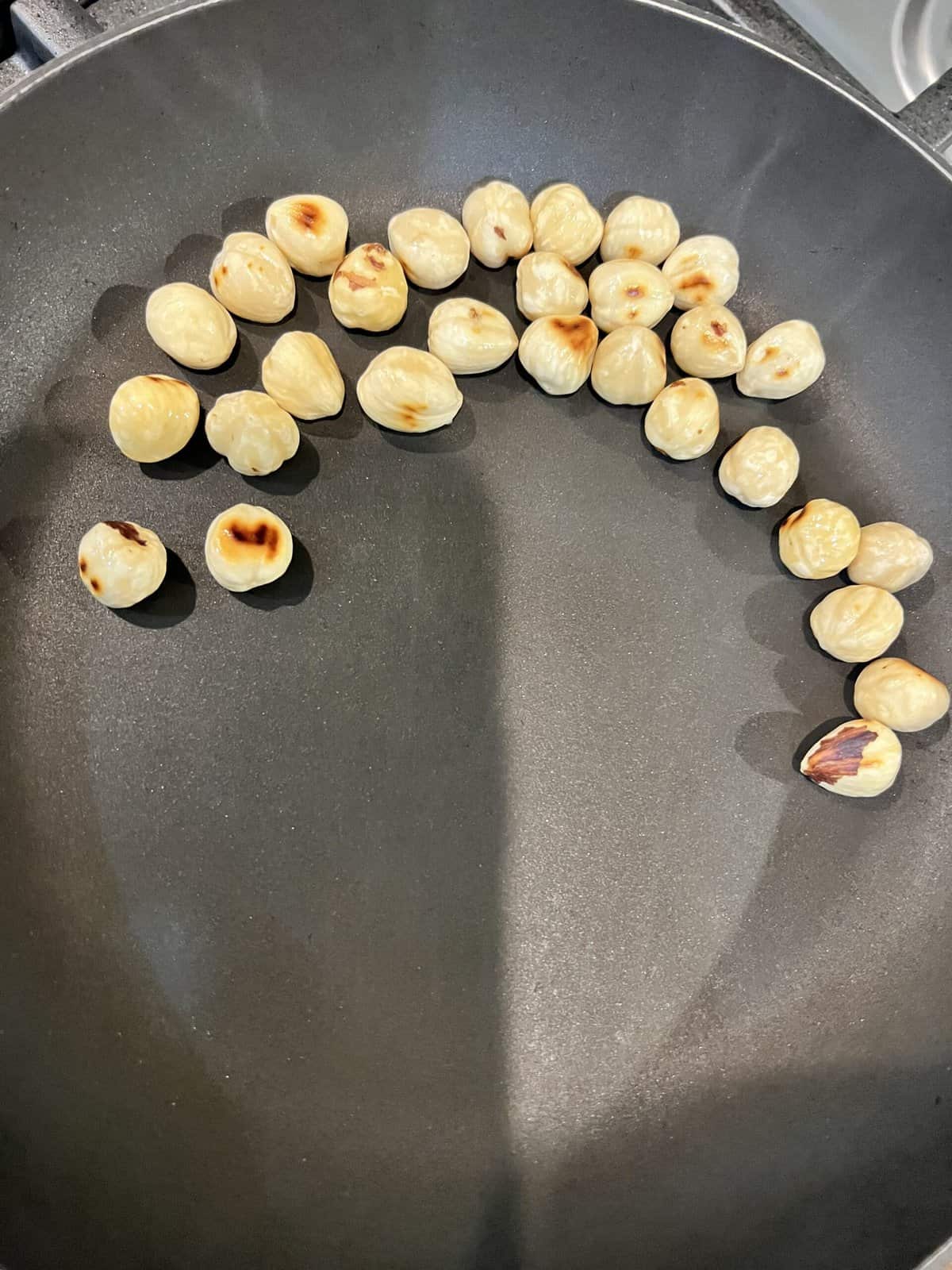 Nonstick frying pan with toasted hazelnuts.