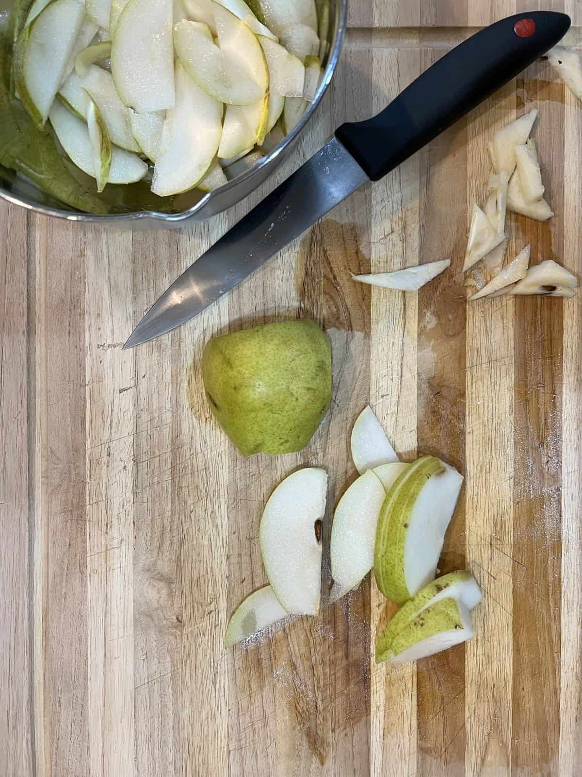 cutting board with knife and half sliced pears.