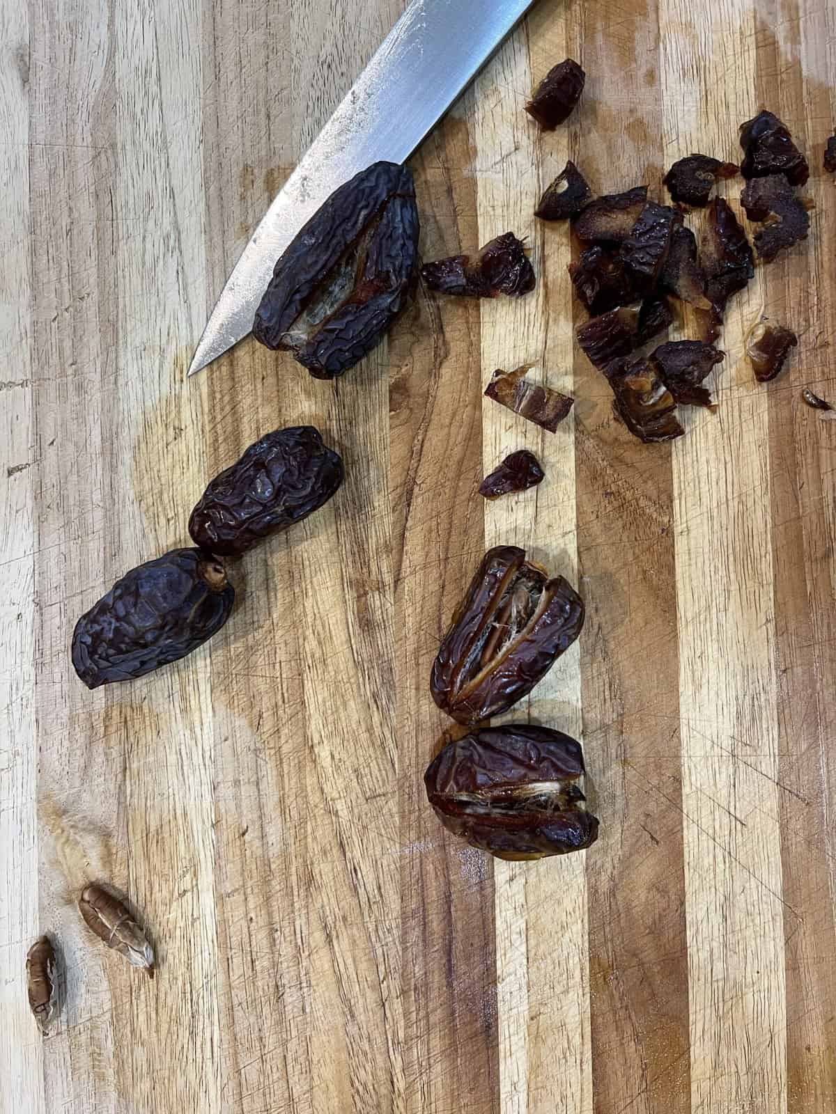 cutting board with knife and half chopped dates.