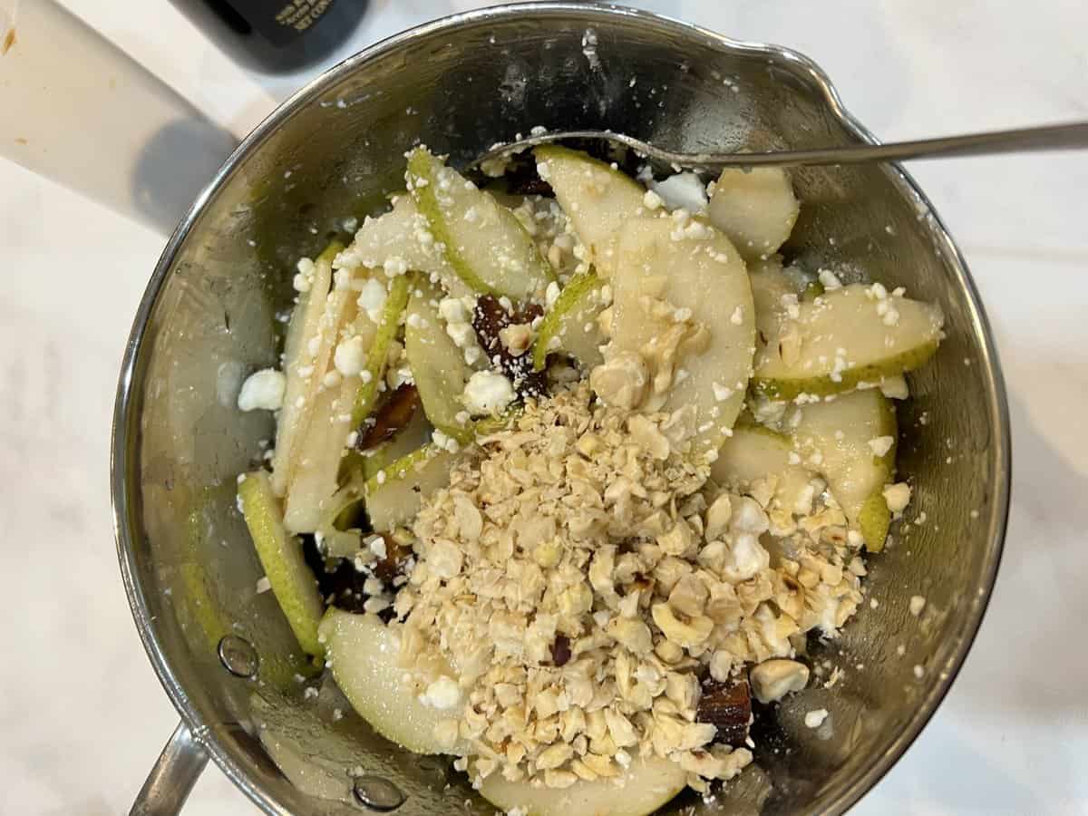 chopped hazelnuts mixed with pears and dates in a metal bowl.