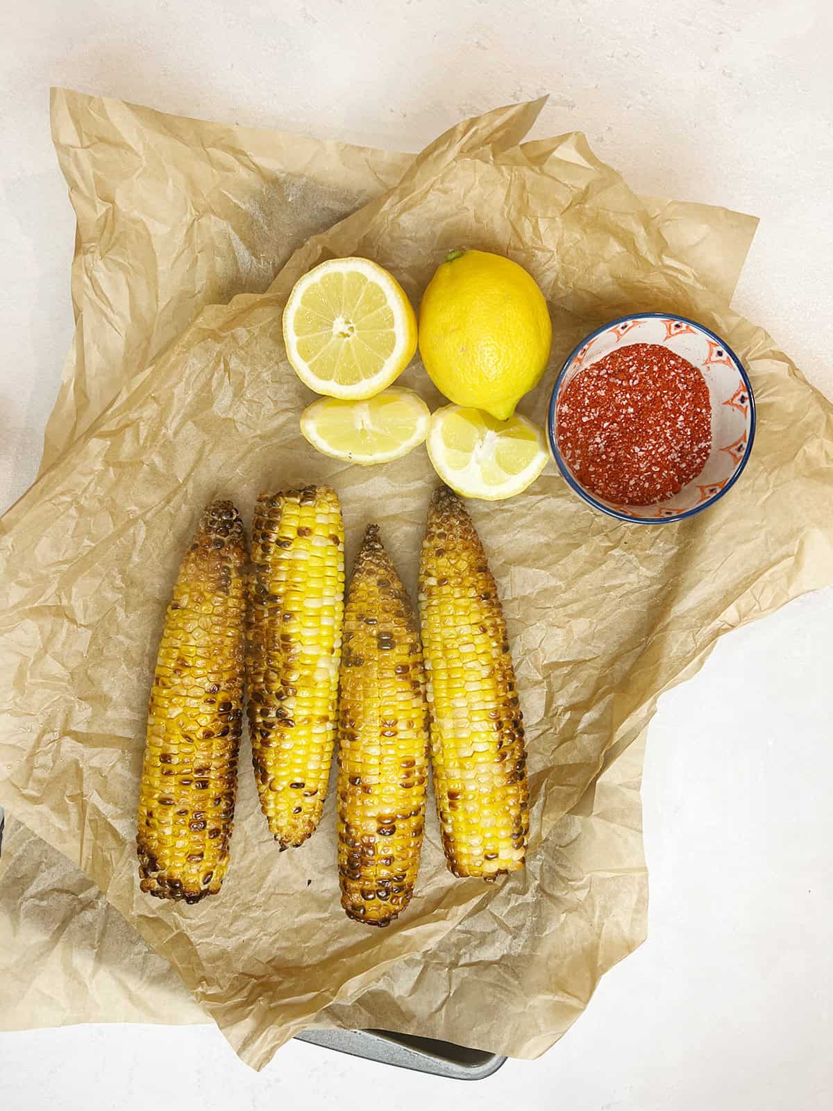 Air fried Pakistani street style corn with lemon and spices on the side.