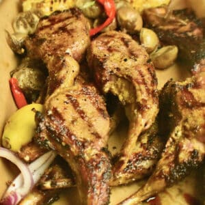 Tandoori grilled lambchops in a tray lined with parchment paper, served with grilled corn, roasted baby egg plants, pickled red thai chilies and fresh lemon.