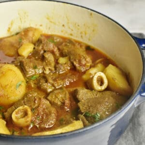 Cooked Aloo Gosht (Pakistani Meat & Potato Curry) in a blue pot.