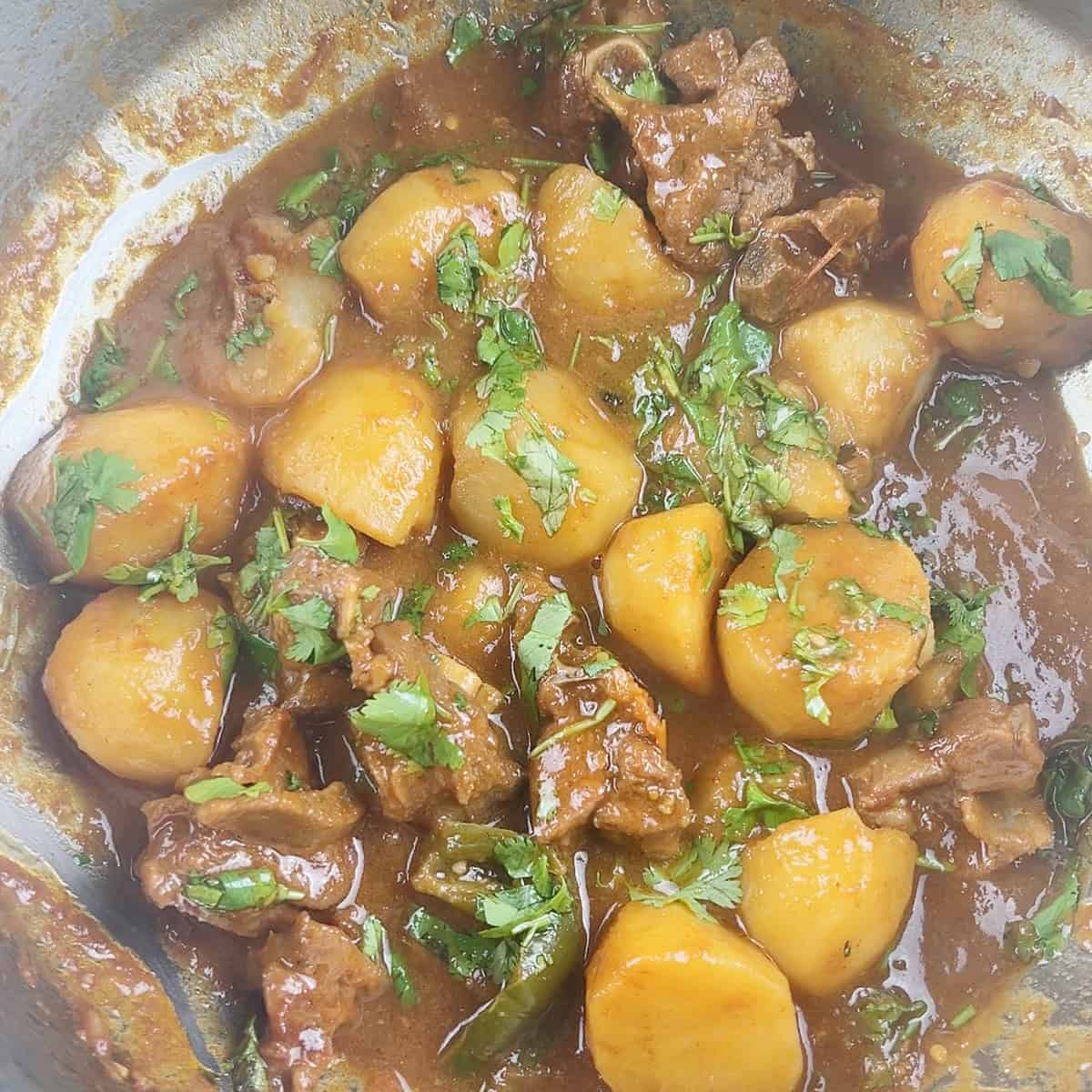 Aloo gosht garnished with cilantro.