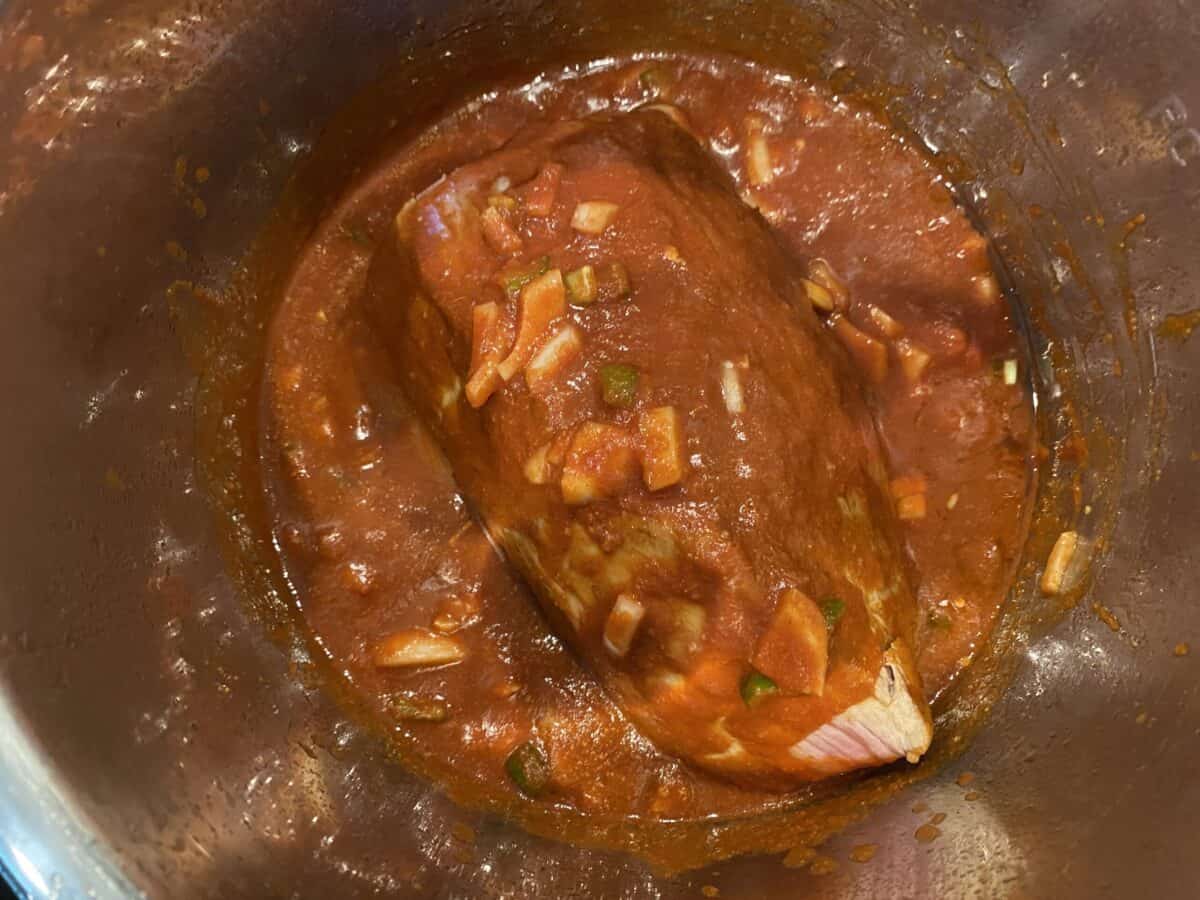 Beef eye of round in an instant pot, covered in a reddish brown marinade.