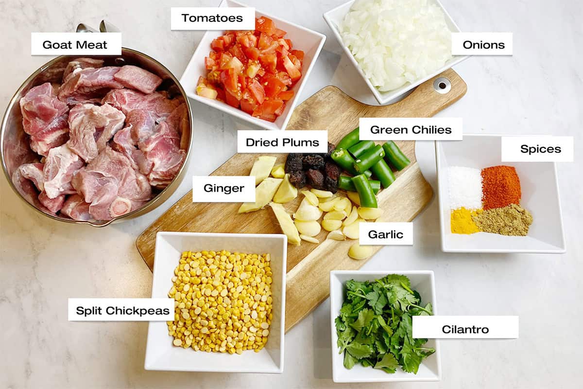 Prepped ingredients for a meat and lentil curry are resting on a white kitchen counter.