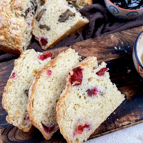 Sliced cranberry walnut soda bread, served with butter and jam.