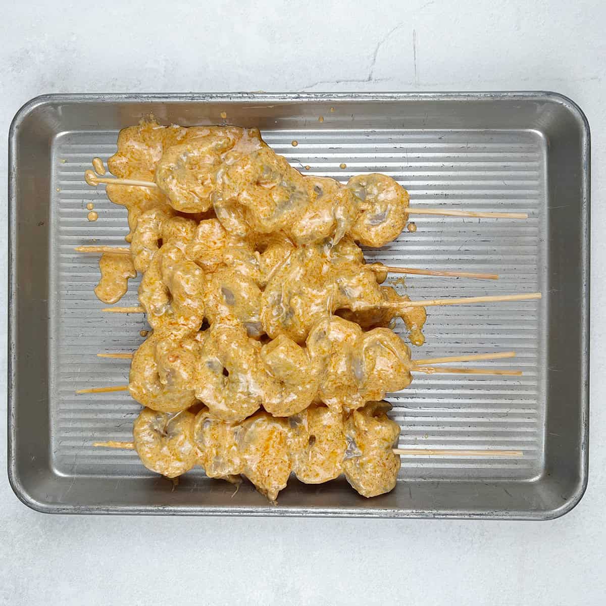 Tandoori shrimp on skewers in an air fryer tray.