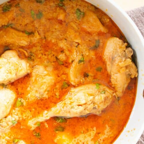 a small cooking pot resting on a brown napkin is filled with a freshly cooked chicken curry recipe.