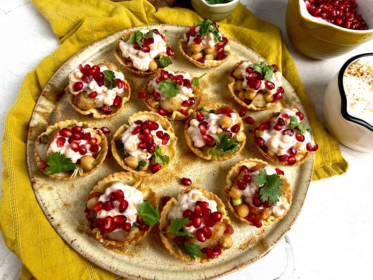 Papdi chaat appetizer cups are ready to serve in a beige pottery platter.