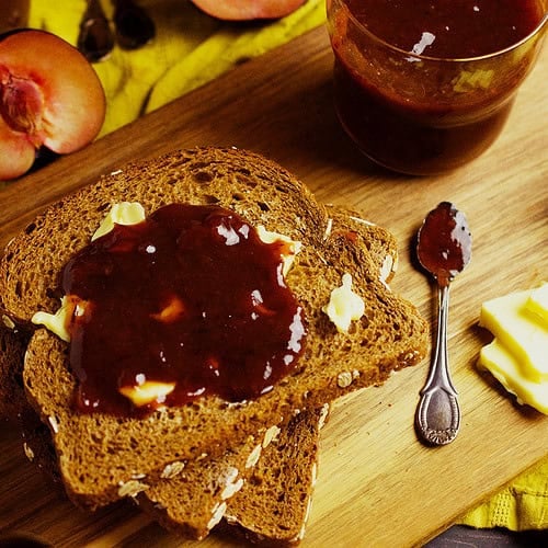 Homemade easy Plum jam is spread on bread along with some butter.