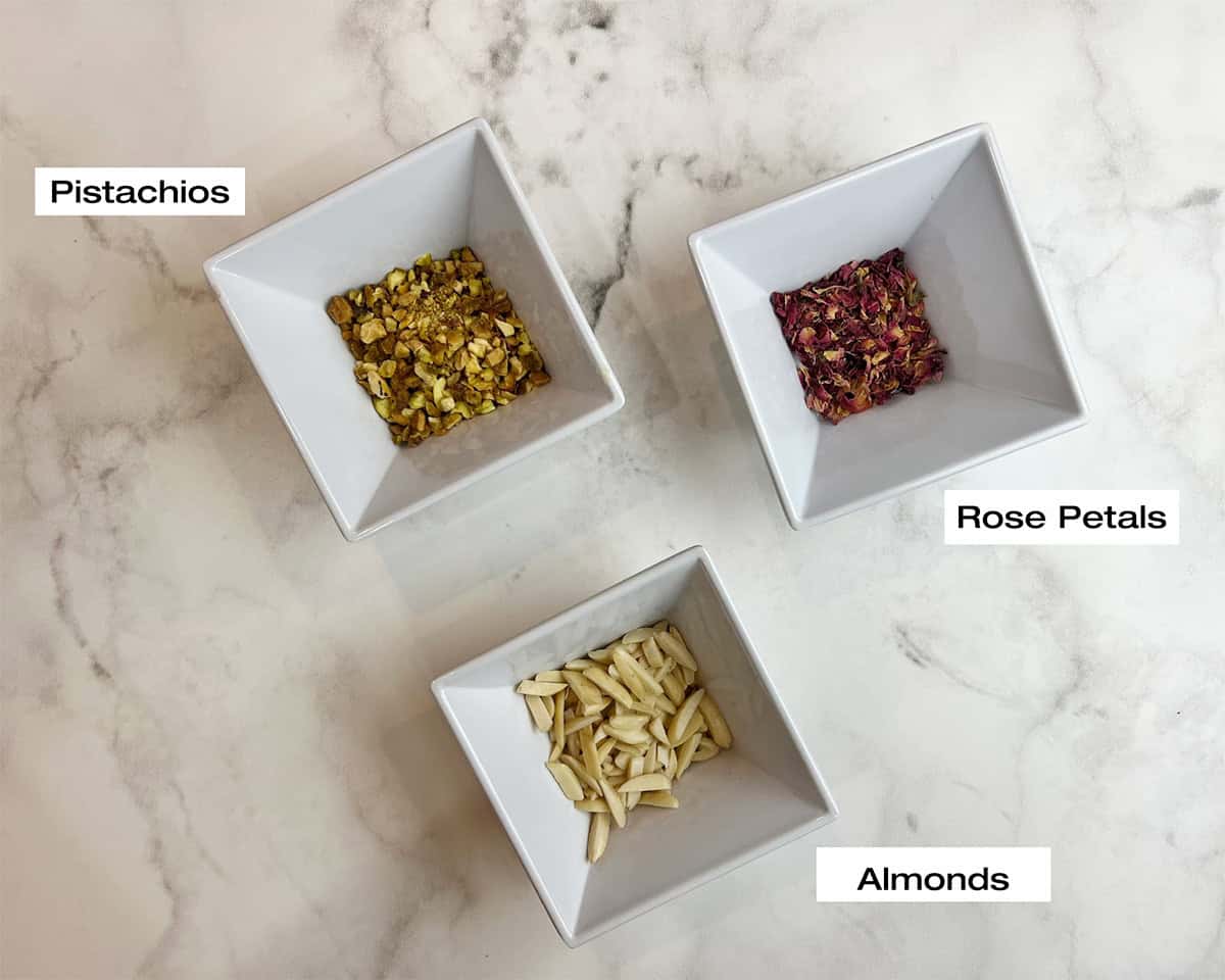 Almonds, pistachios and dried rose petals are measured and ready to garnish a Pakistani pumpkin dessert recipe.