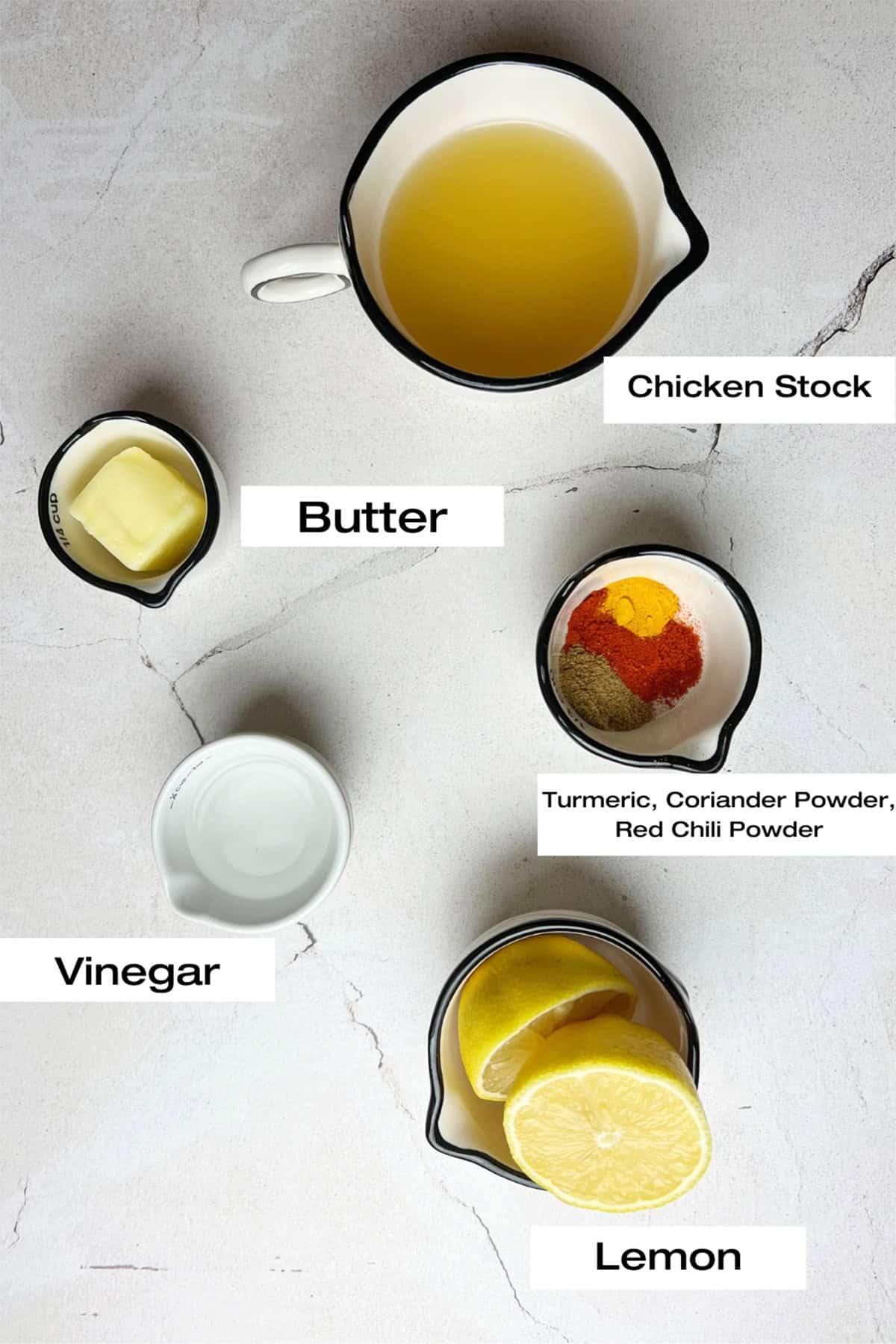 Measured ingredients for an injection to help marinate a roast chicken are laid out on a white kitchen counter.