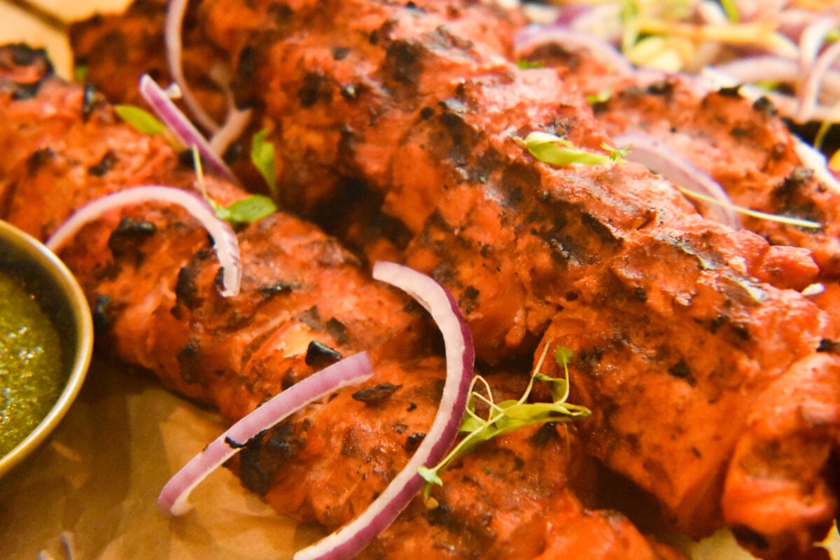 Skewered chicken tikka boti with some green chutney, red onions and cilantro microgreens.