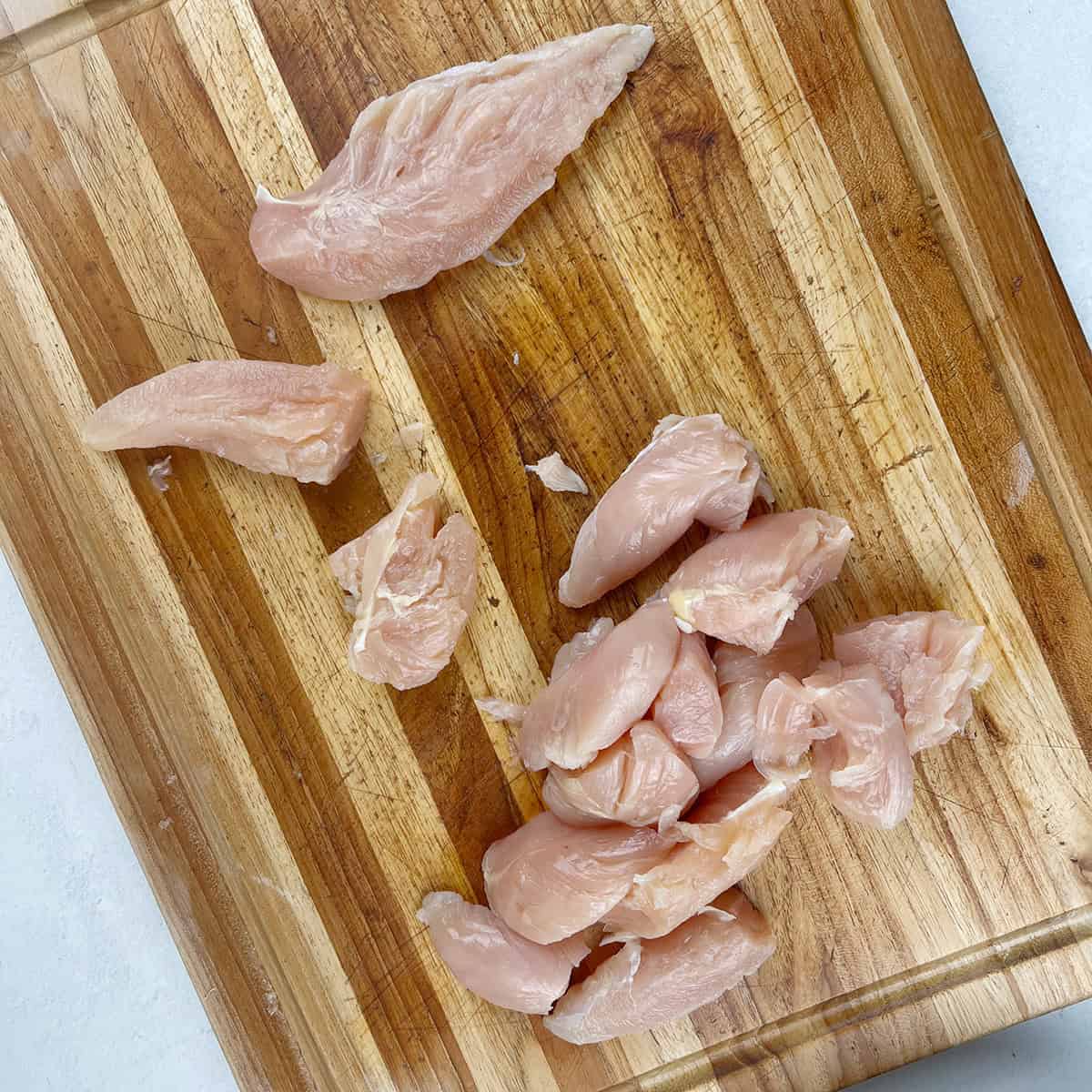 Chicken tenderloin being cut up into pieces.