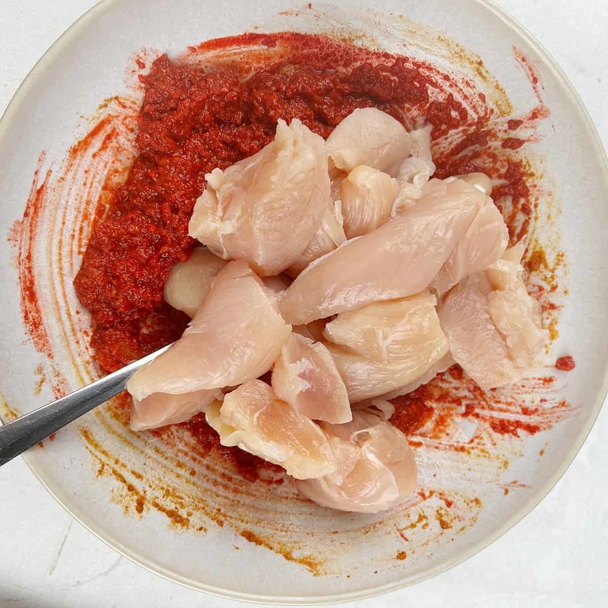 chicken pieces being mixed with a marinade.