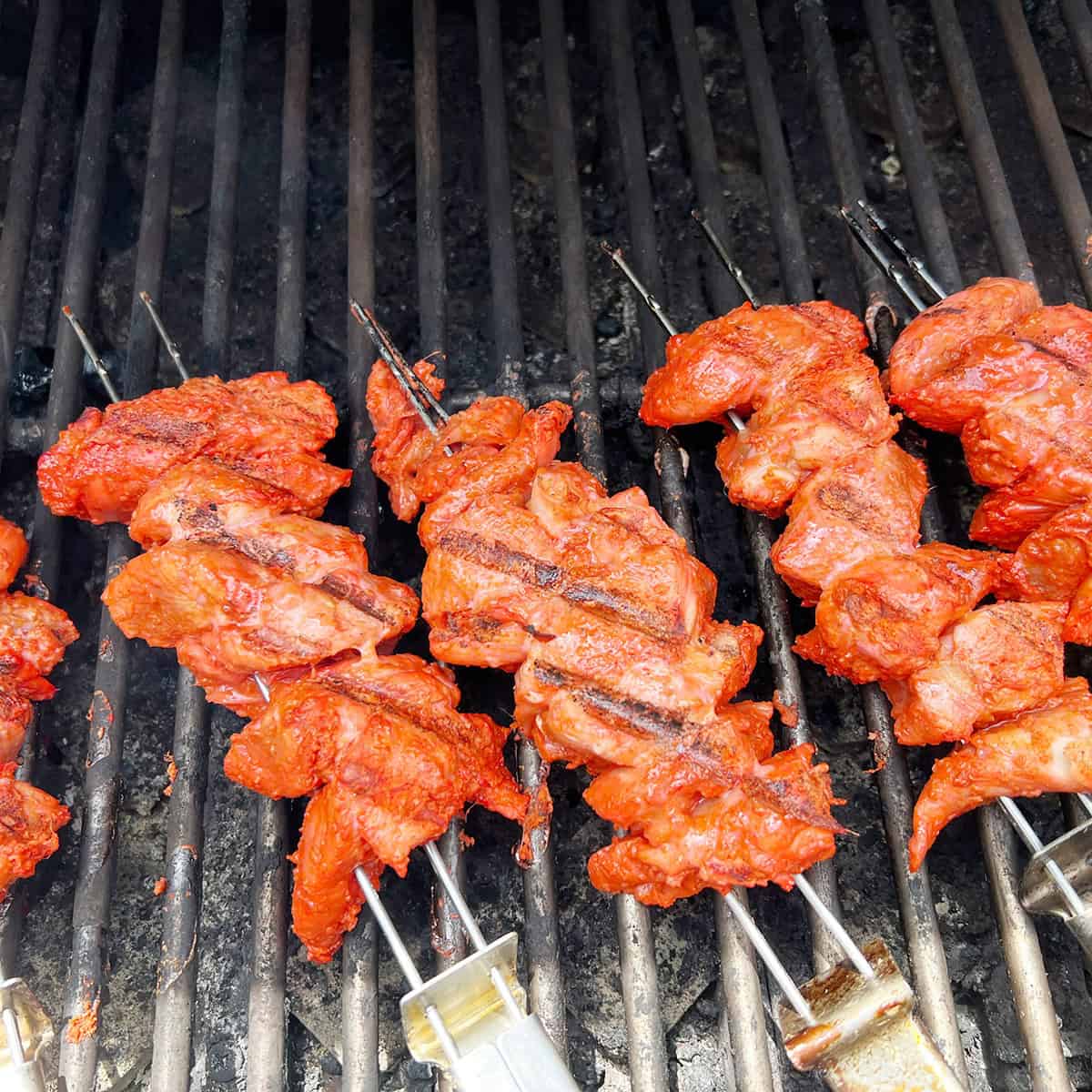 Chicken boti kabab on a grill.