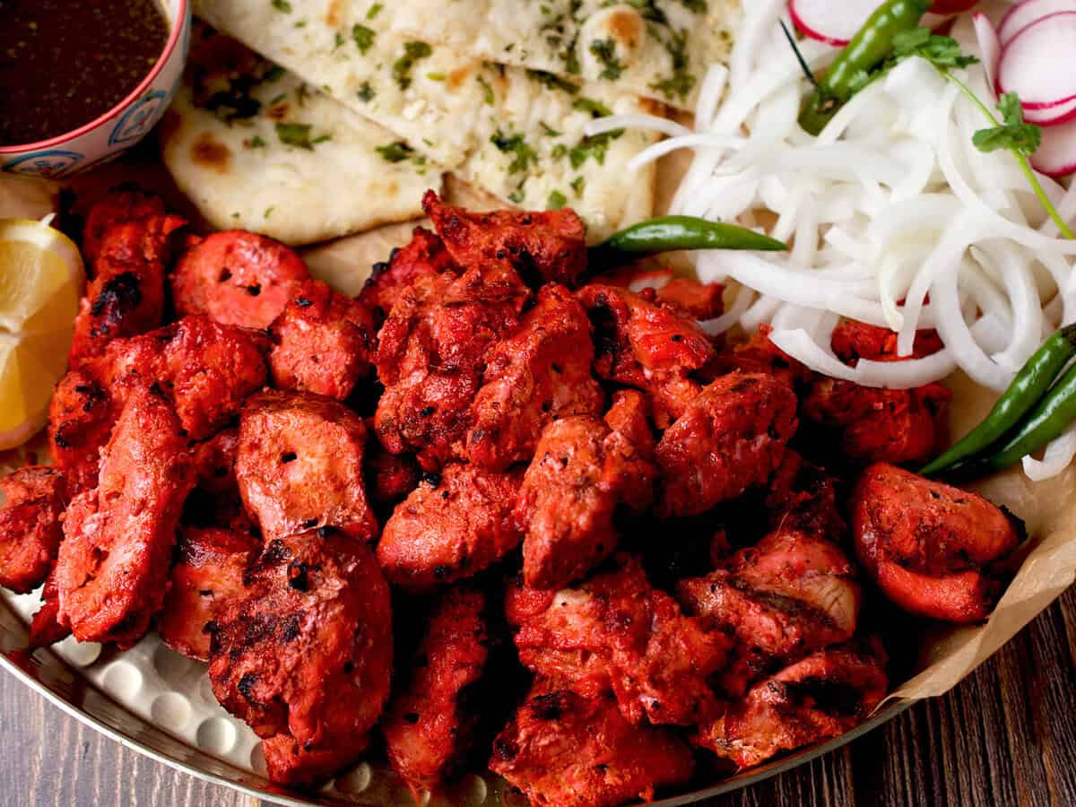 Chicken tikka boti served with onions, chutney, and naan.