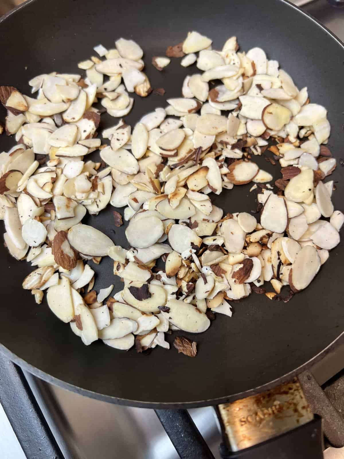 A black frying pan filled with almonds.