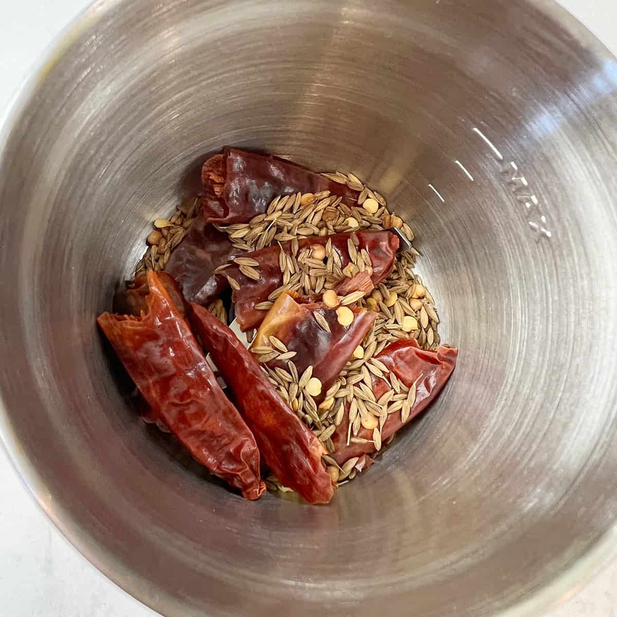 Toasted cumin seeds and dry red chillies are ready to be ground to a powder.