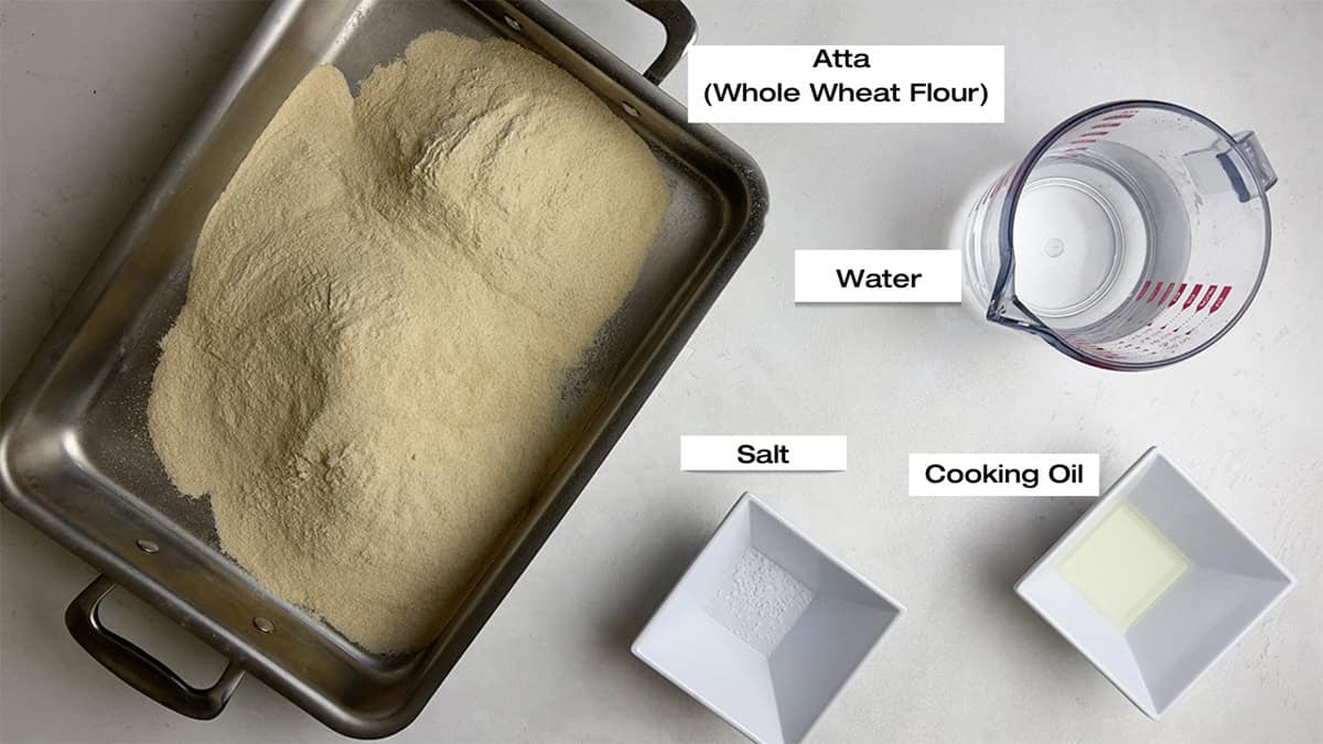 Ingredients for a paratha recipe are measured and laid out on a white kitchen counter.