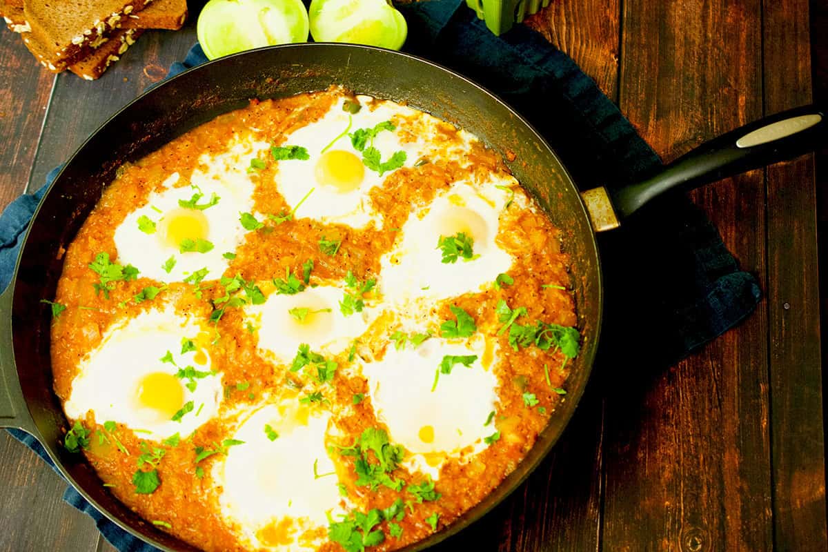 Freshly cooked poached eggs in a green sauce are  ready to be eaten.